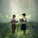 Two children reading books in a forest